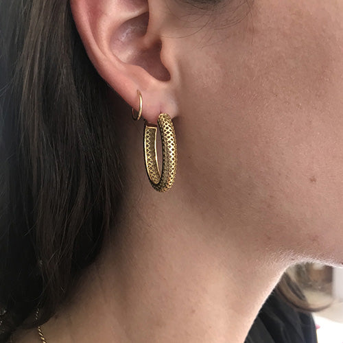 A woman wearing a pair of gold hoop earrings.