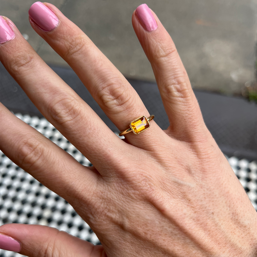 A mandarin garnet ring displayed on a woman's hand.