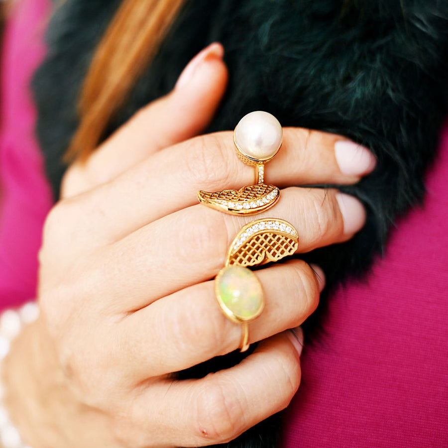 Ring stack featuring a South Sea pearl ring, a butterfly ring and an opal ring all set in 18K yellow gold.