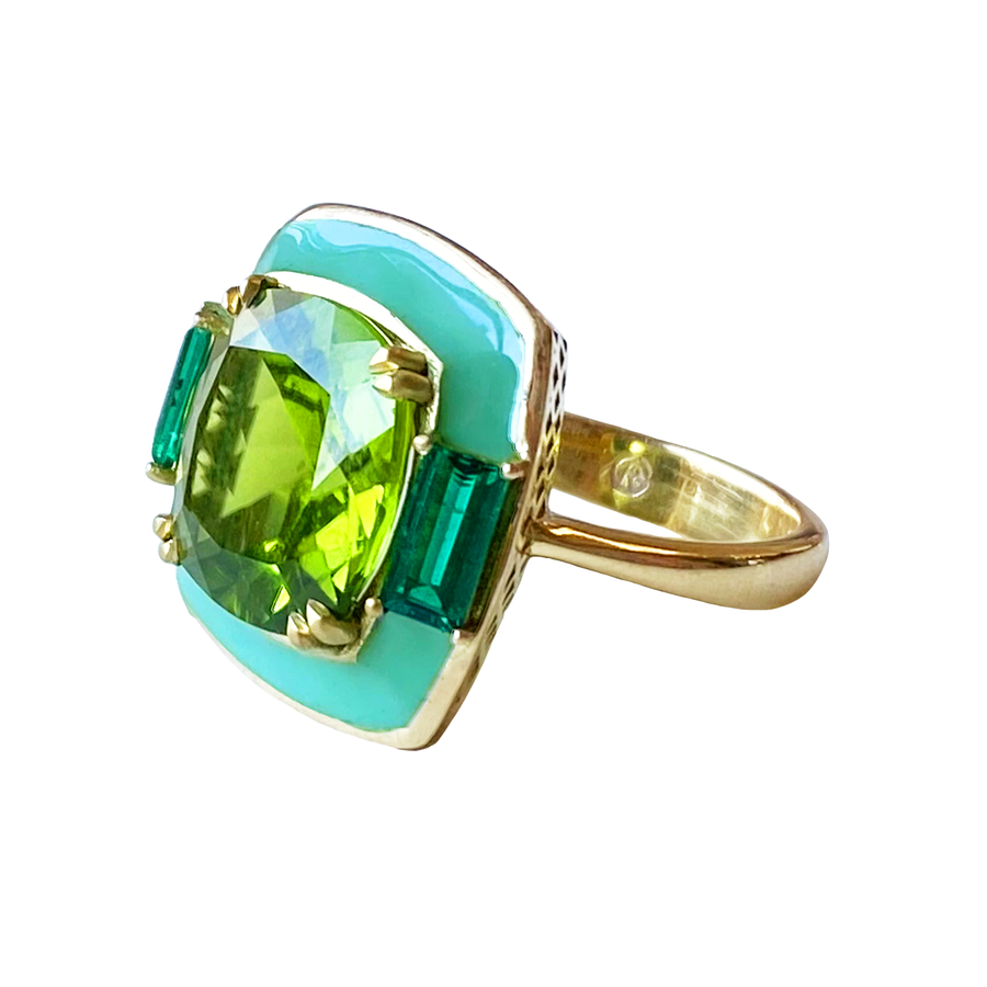 An 18K gold peridot ring featuring two prong set emerald baguettes and aqua enamel.